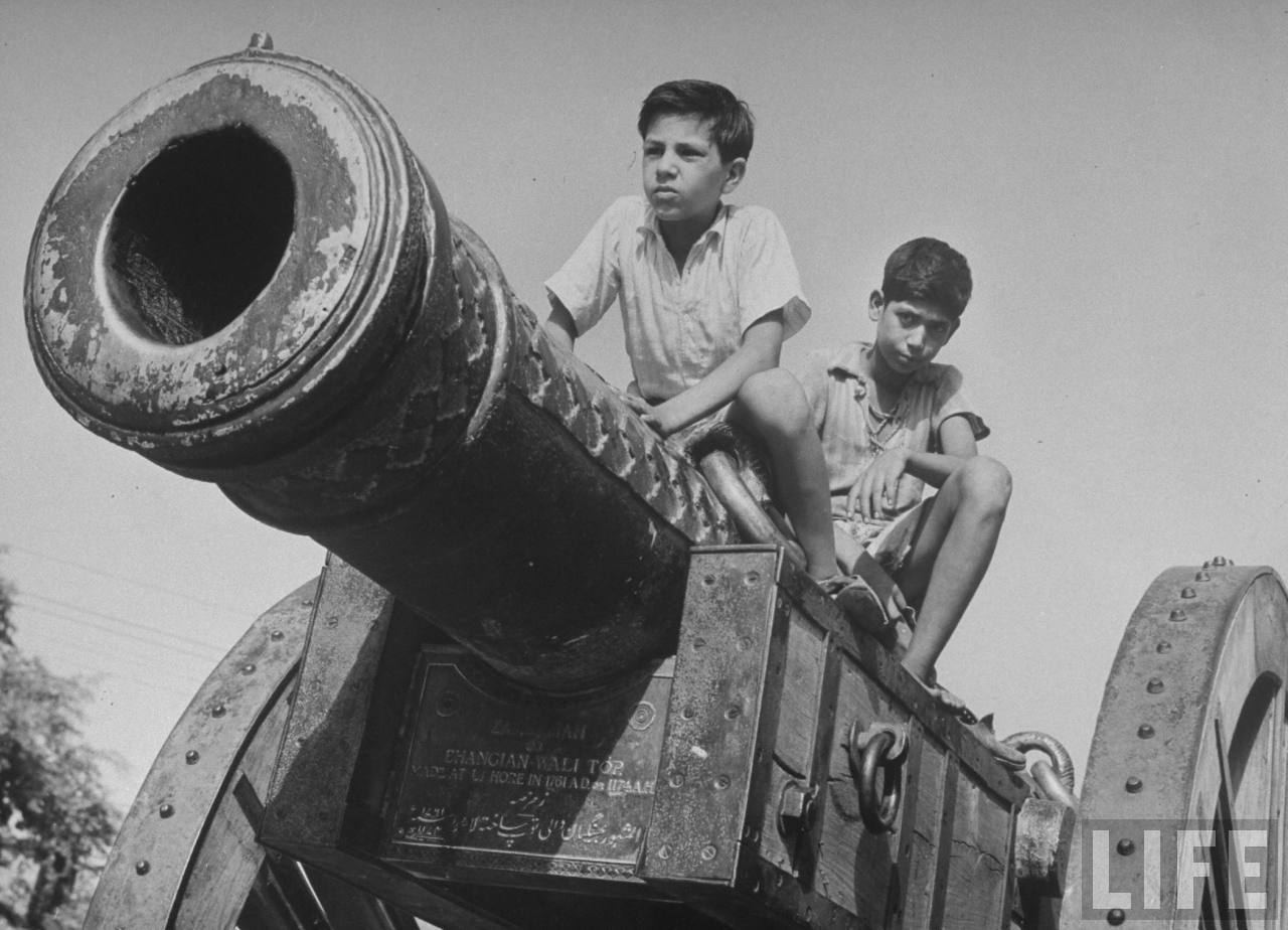 Indian boys playing atop an old military cannon built in 1761 which stands on the grounds of the Jubilee Museum & Technical Institute, Prince Albert Memorial Museum - Lahore 1946